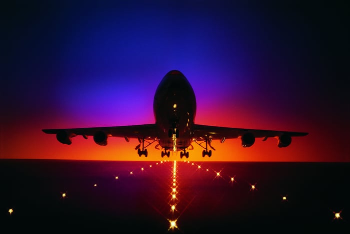 Airplane just above a runway at twilight.