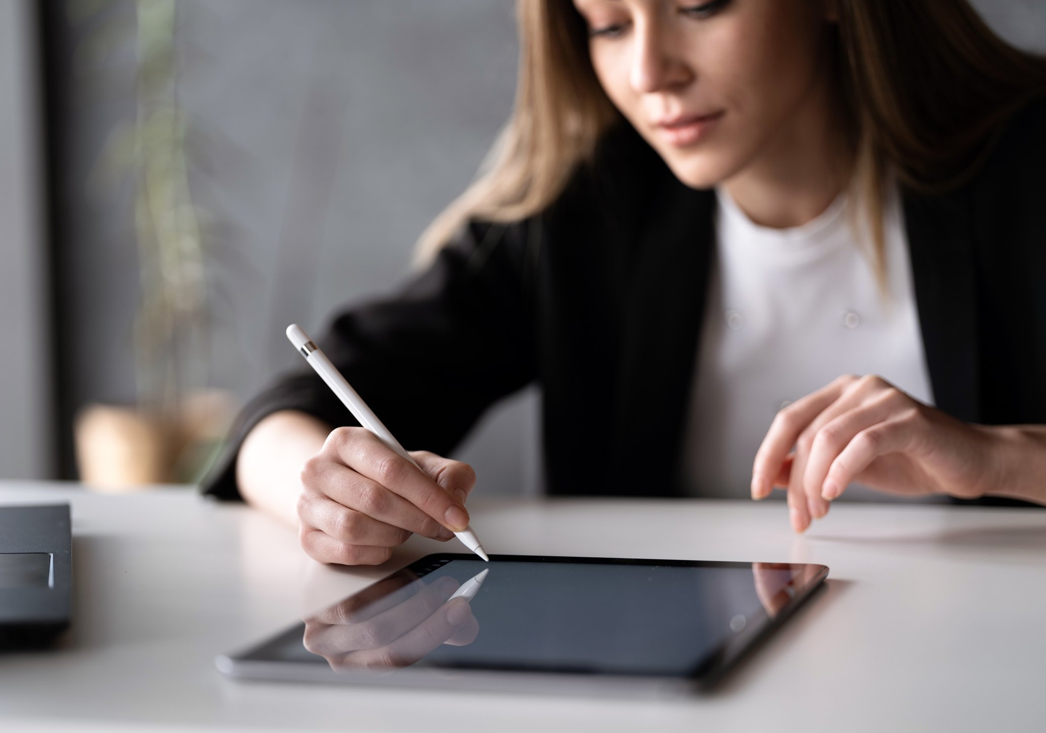 Woman signing document on tablet with stylus.
