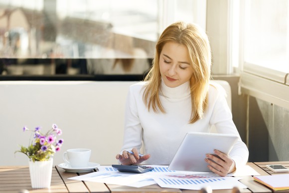 Woman using a calculator while reviewing financial documents.