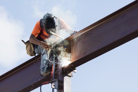 A worker welds a steel girder.