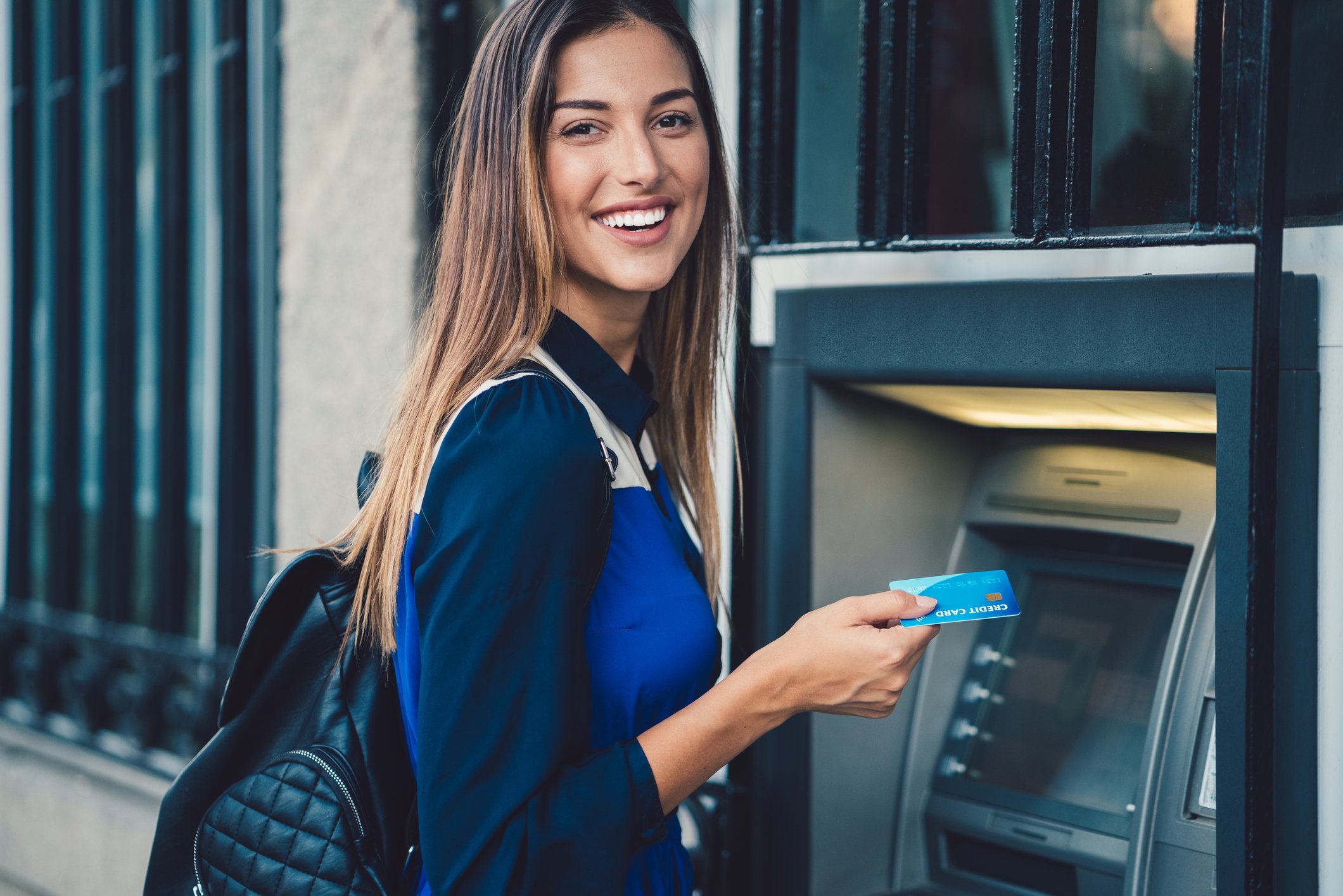 Person smiling as they use an ATM.