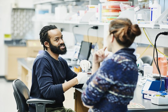Two workers talking in a biotechnology laboratory.