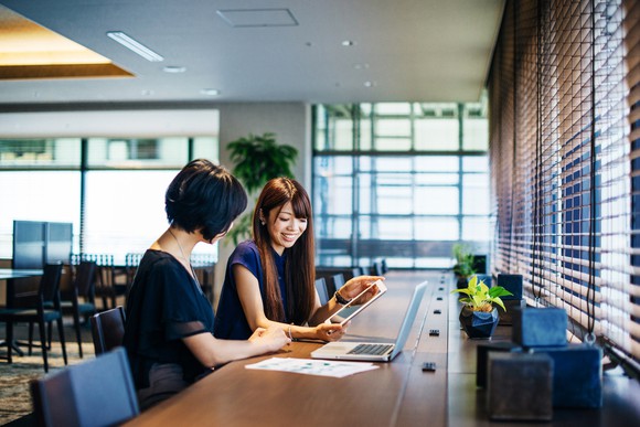 Two ladies working on a project together in an open room.