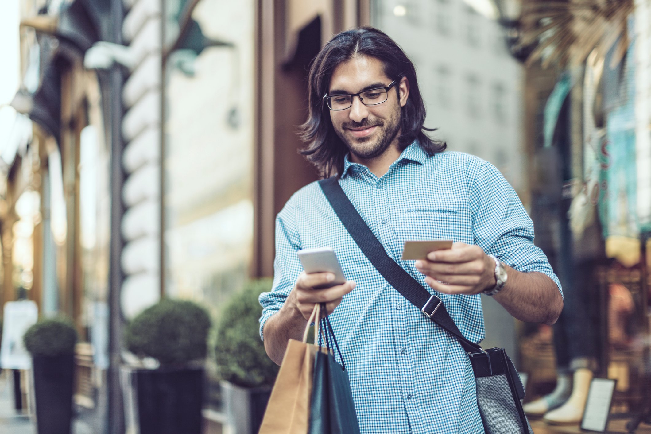 A shopper makes a purchase on a smartphone while outside.
