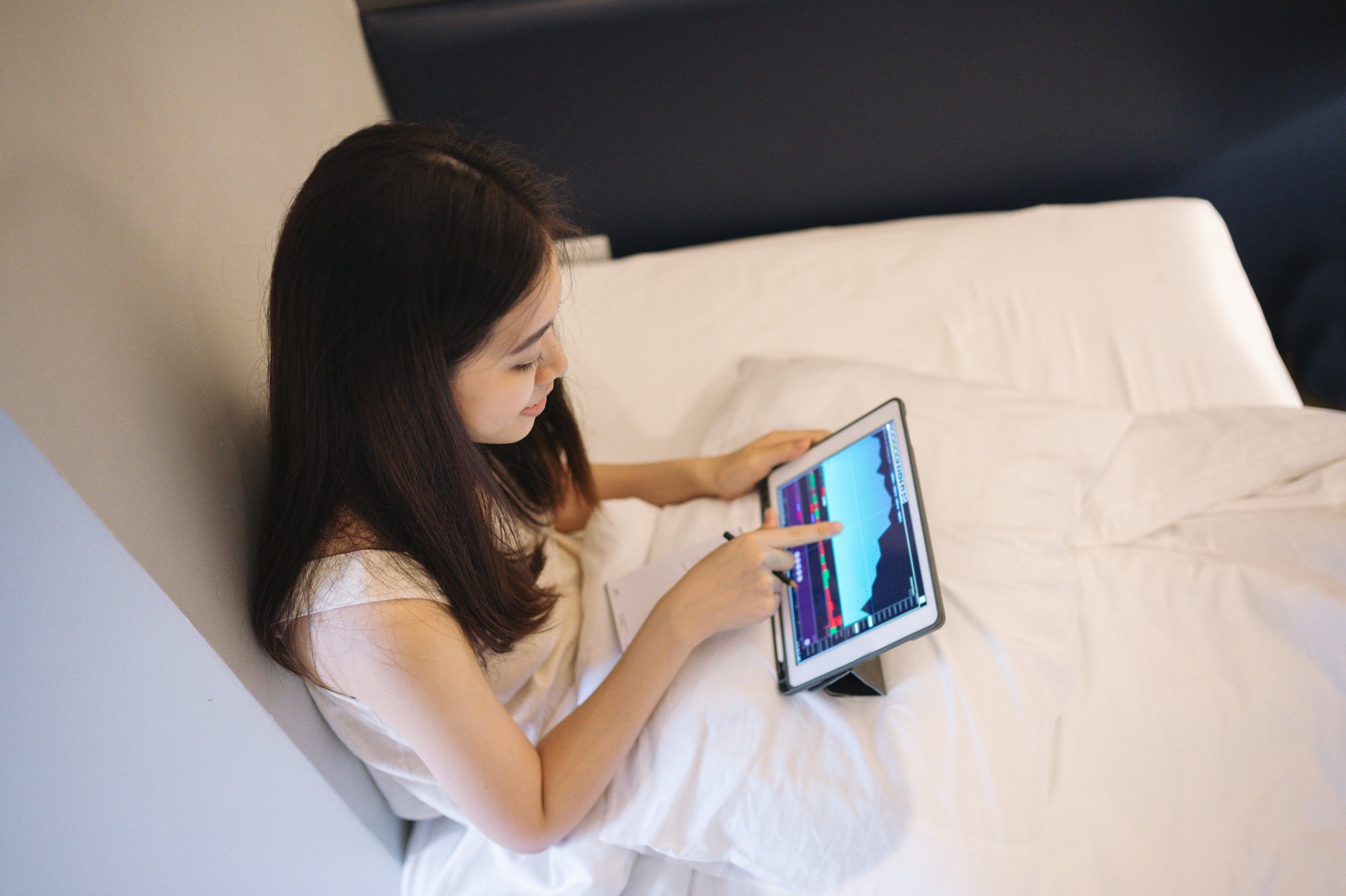 Investor at home studying a stock chart with tablet computer.
