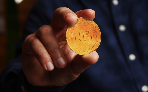 Hand holding an NFT coin.