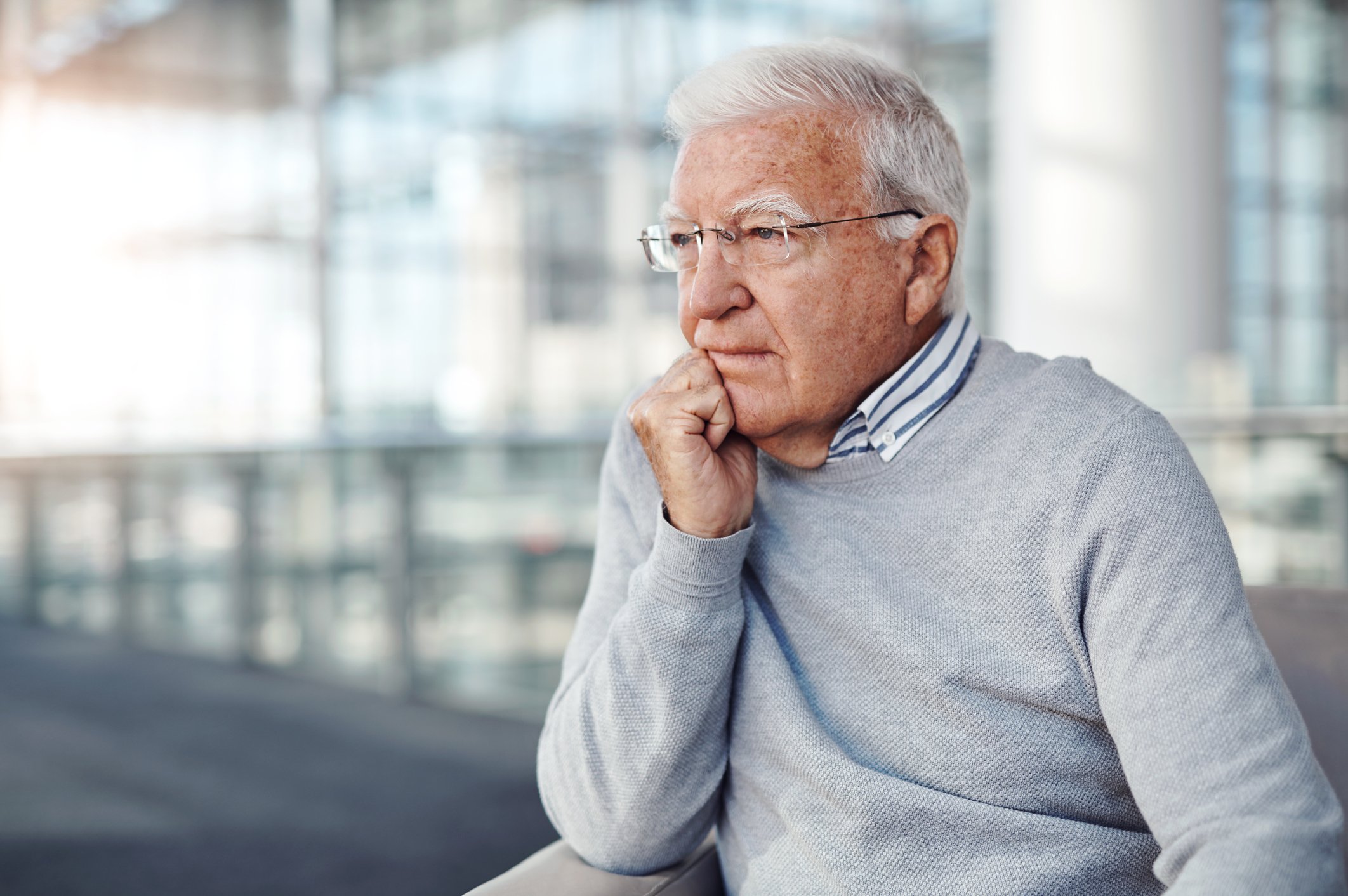 a senior man looks out the window