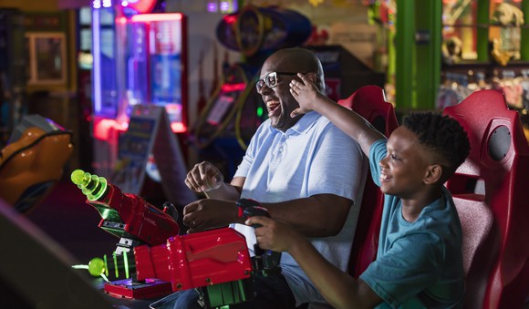 A father and son playing a competitive arcade game.
