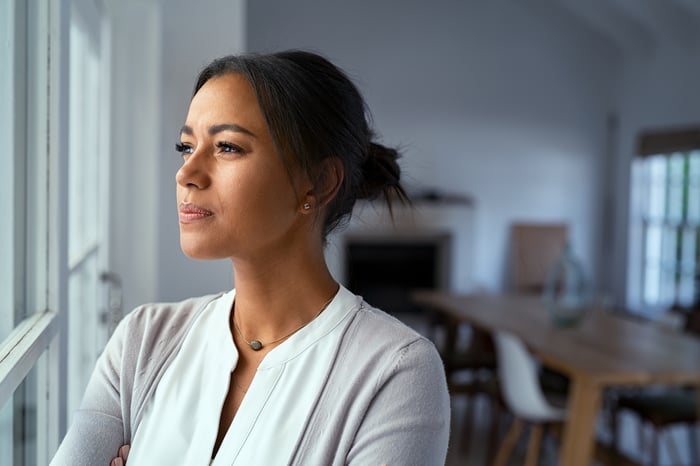 Person looking out a window, looking concerned.