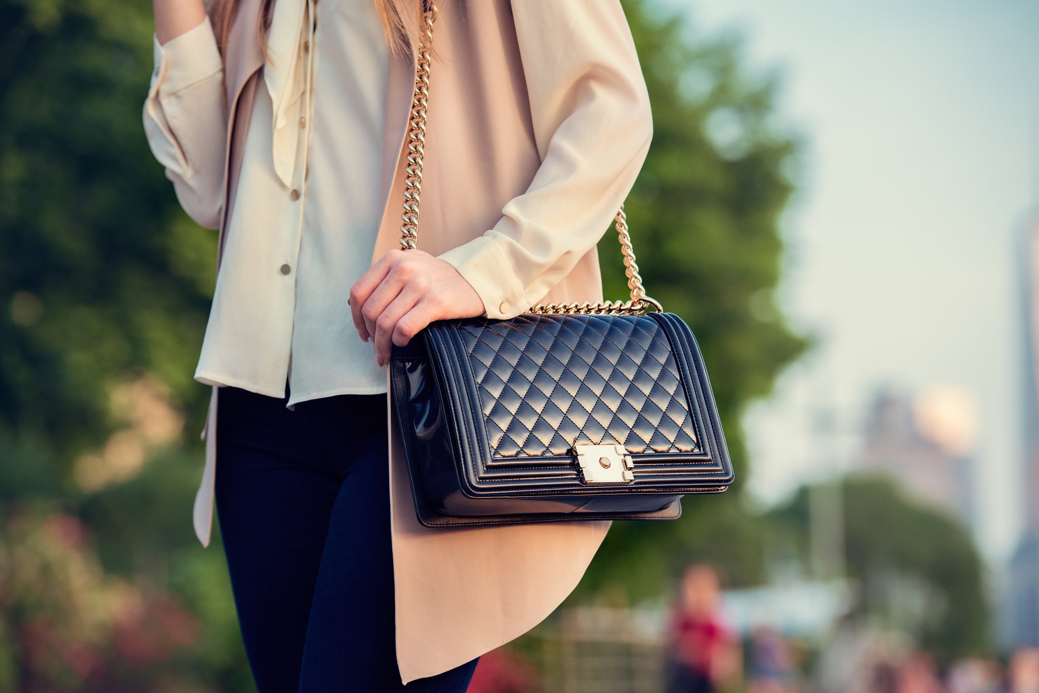 A person holding a luxurious black handbag.