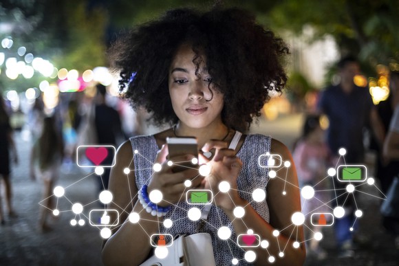 Woman looking at phone with overlay of connected icons representing connection to the internet.