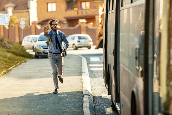 Man running late, chasing a bus as it drives away.