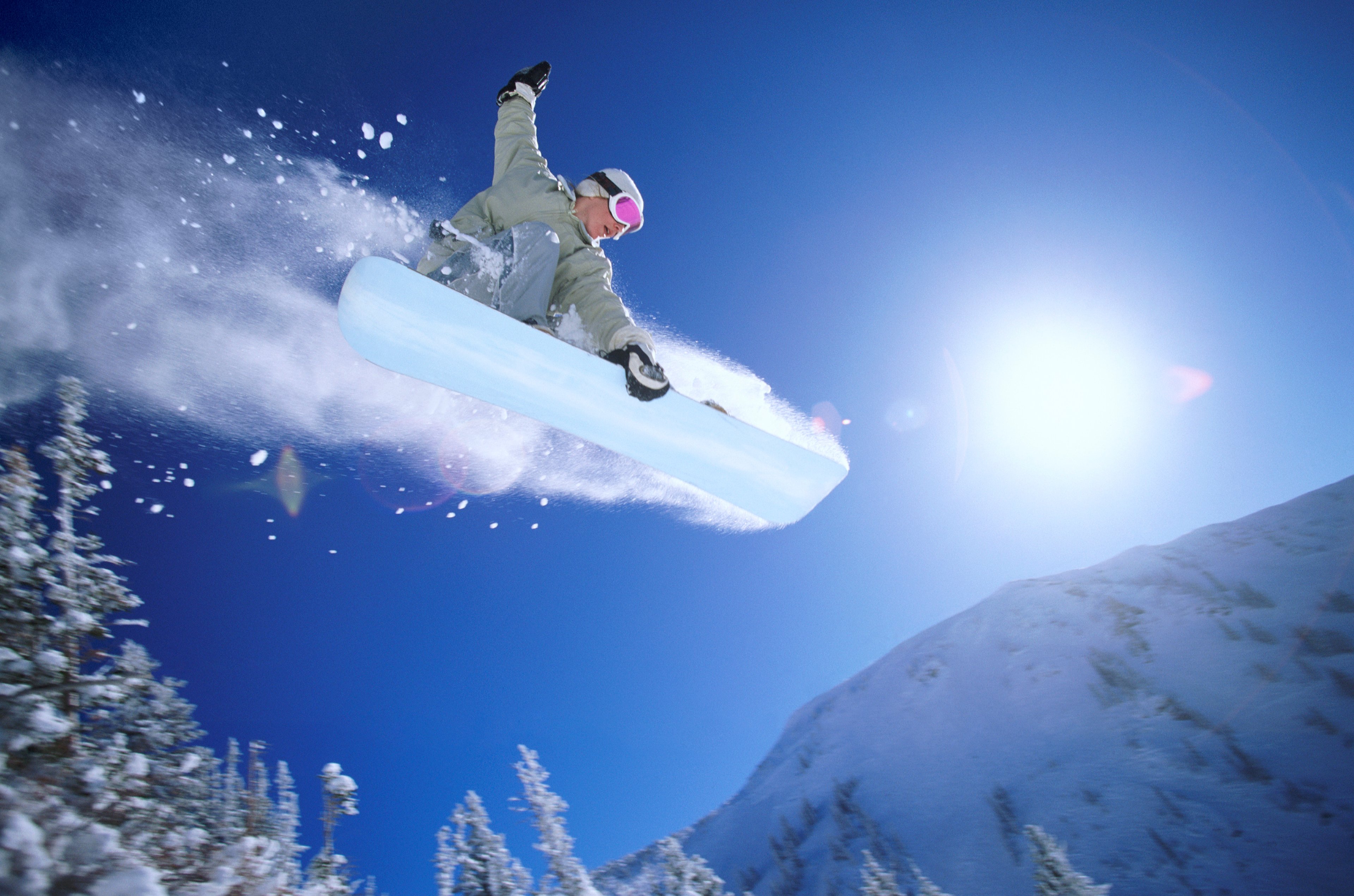 A low angle view of a person snowboarding mid air.