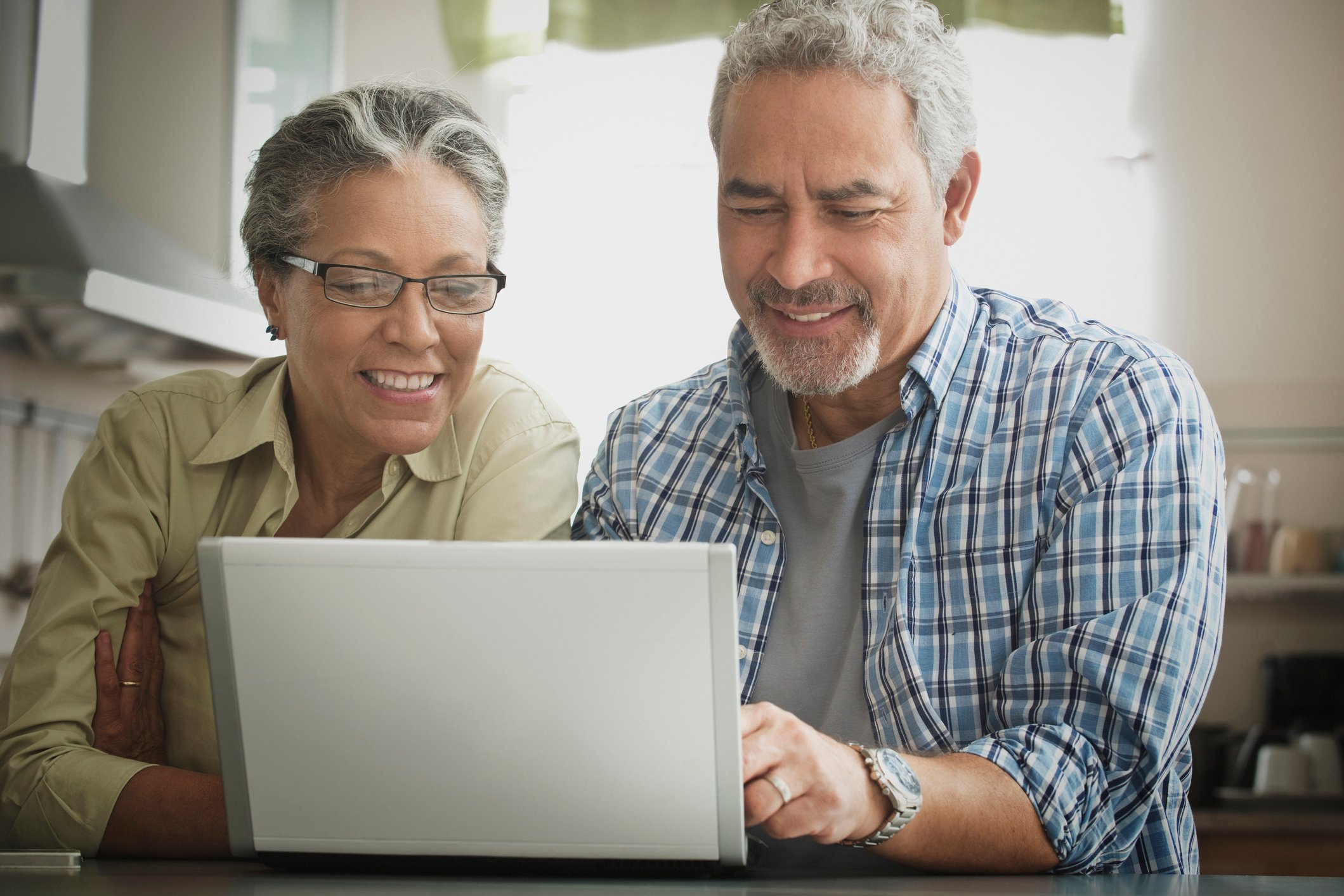 Two investors look at something on a laptop at home.