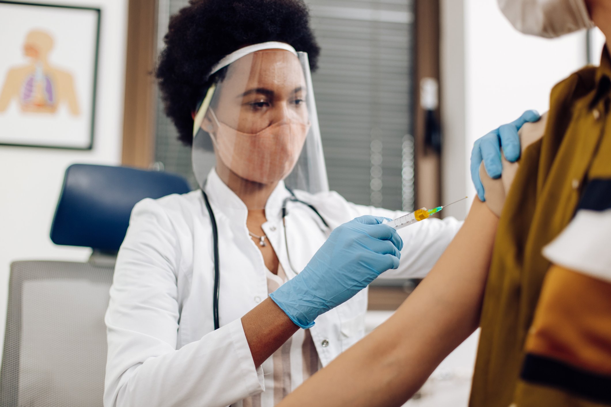 A healthcare worker vaccinates a patient in a medical office.