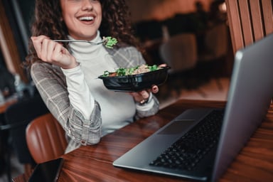 person eats to go salad while working at computer