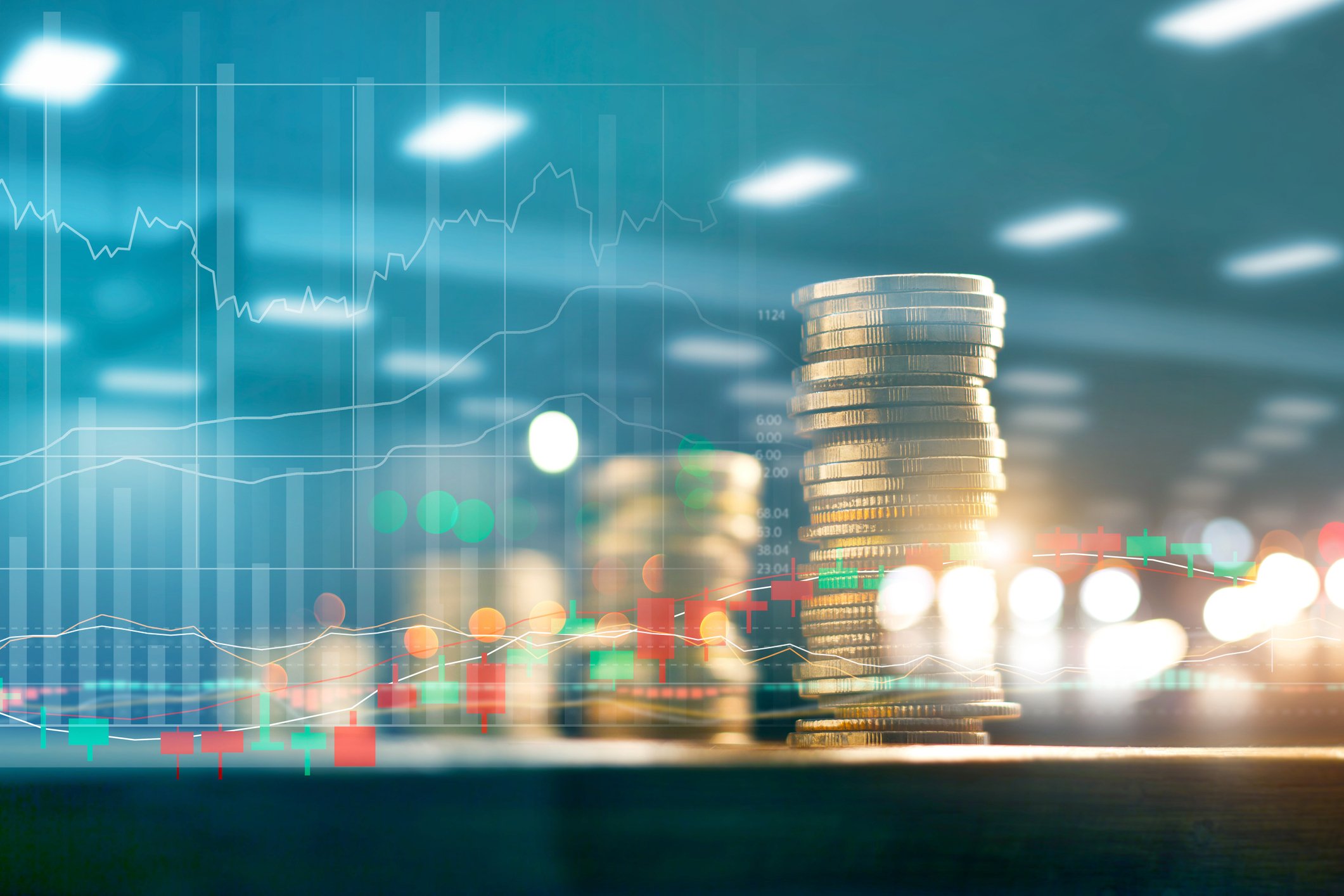 Coins stacked up on table, with market chart overlayed in background.