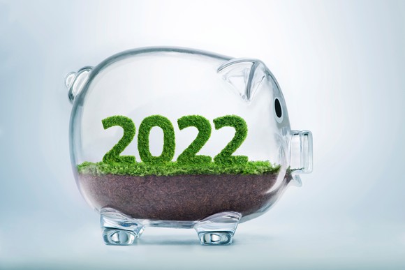 Glass piggybank with plants inside that form the year 2022. 