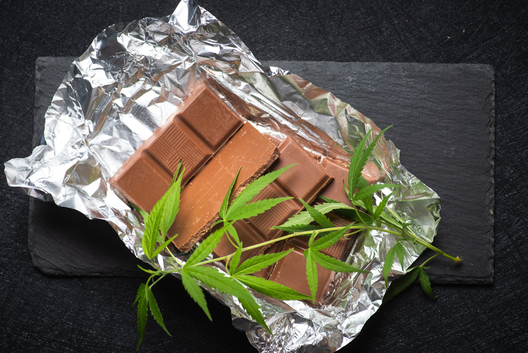 Marijuana leaves and chocolates on a foil.