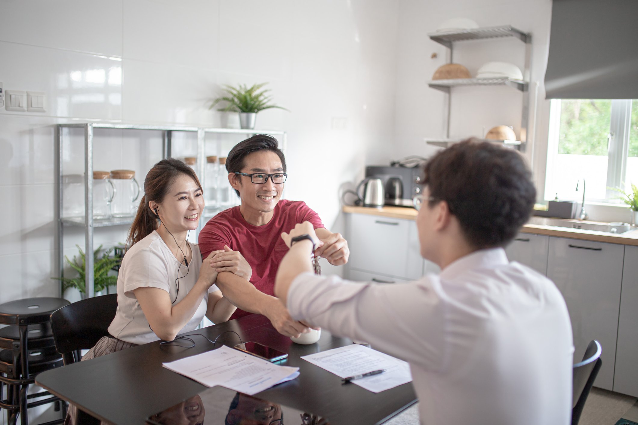 A couple and an adviser shake hands as they complete paperwork.