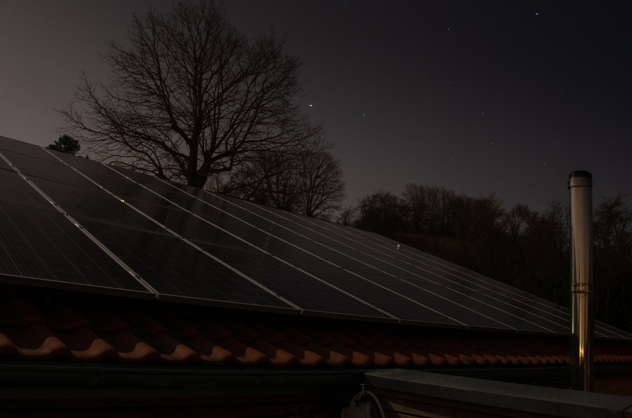 Solar panels installed on a roof are facing the night's sky. 