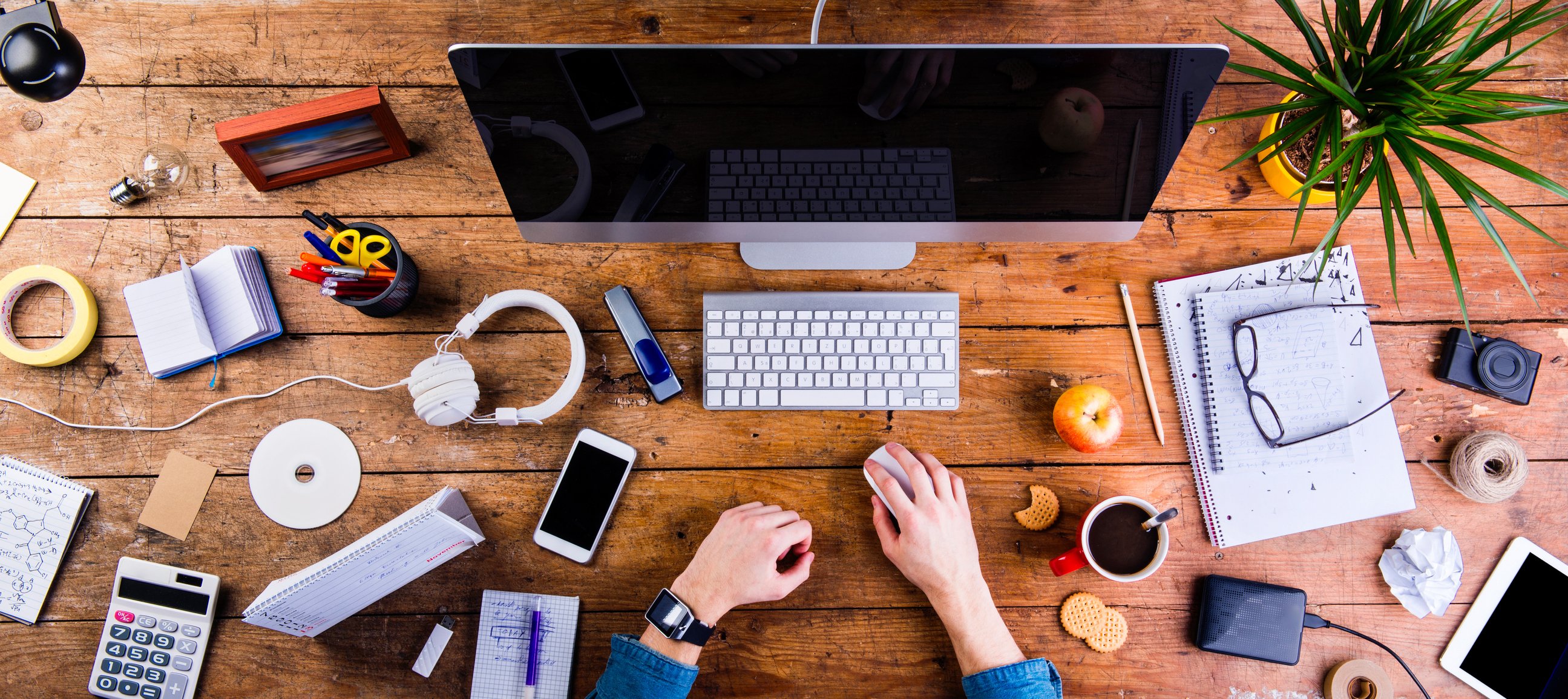 Person using a Mac desktop computer with various other Apple products placed on their desk.