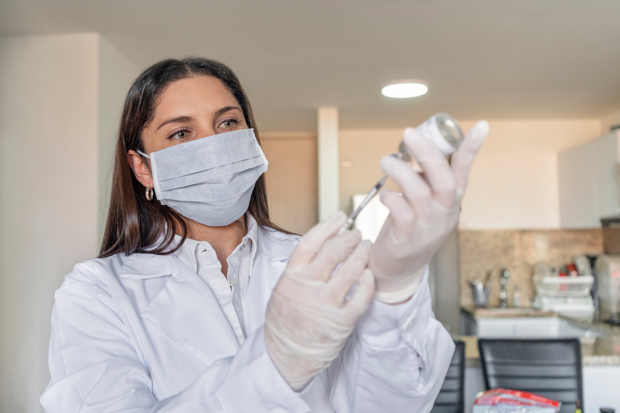 A medical professional loads a syringe while standing in a clinic.