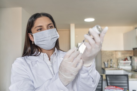 A medical professional loads a syringe while standing in a clinic.