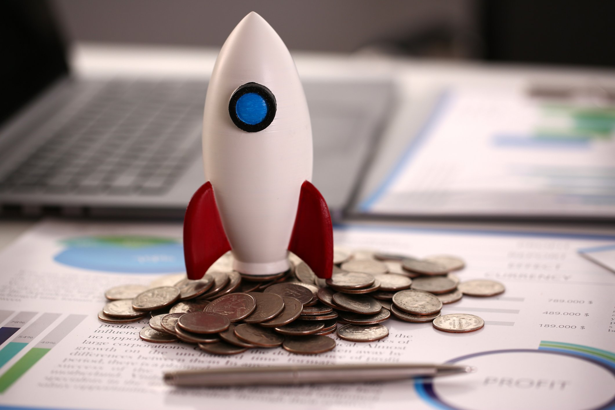 A toy rocket sitting on top of a pile of U.S. quarters.
