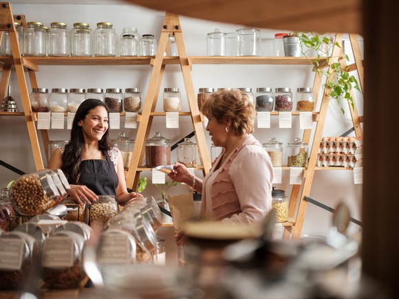A clerk helping another person in a small shop.