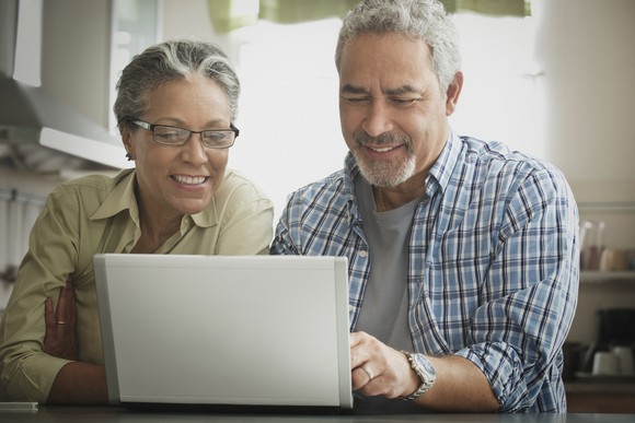 Two smiling people looking at a laptop.