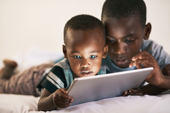 Two kids on an electronic device.