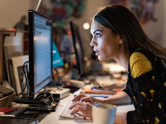 A woman intently focuses on her computer screen. 