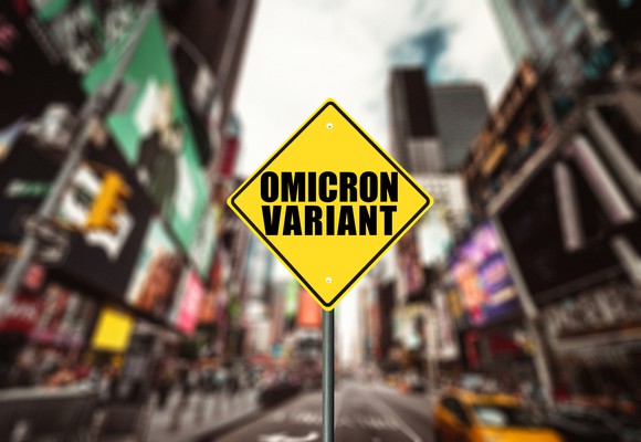 Street sign reading "Omicron Variant" with a blurred city street in the background.