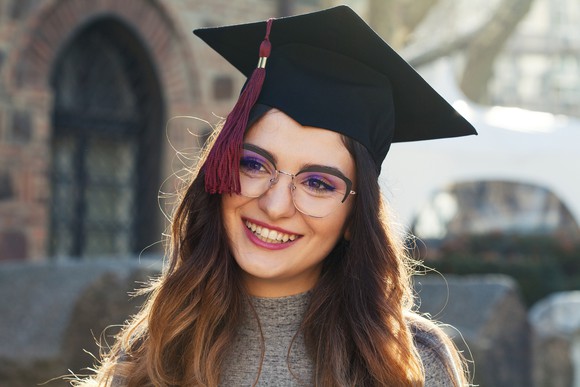 A person smiles and wears a graduation cap.