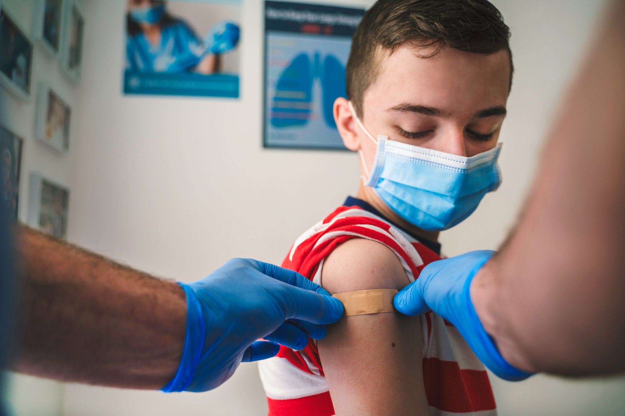 A healthcare provider places a bandage on a child's arm after giving a shot.