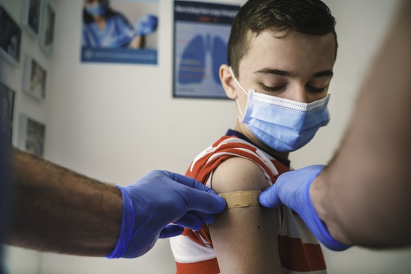 A healthcare provider places a bandage on a child's arm after giving a shot.