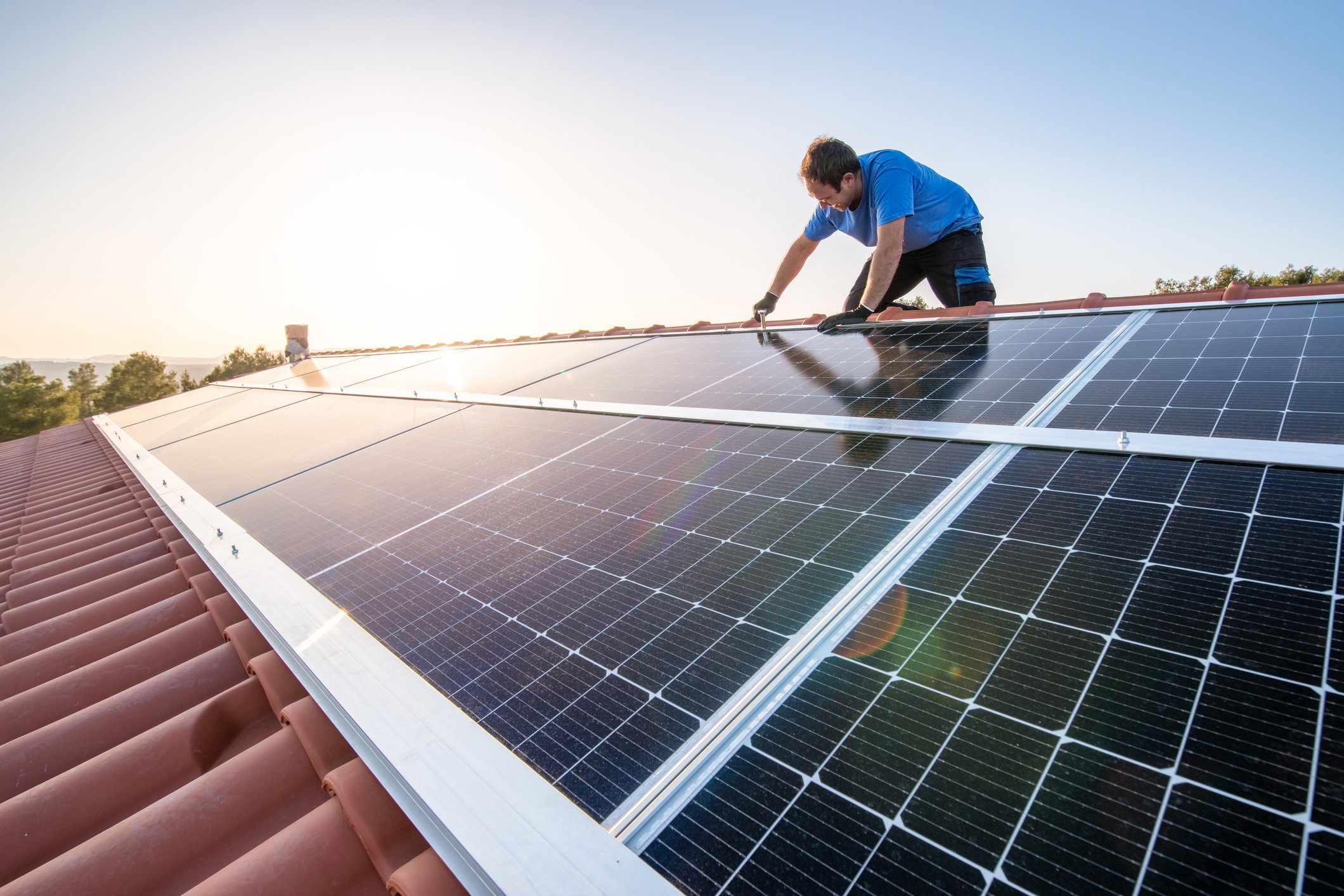 Worker installs solar panels on a roof. 