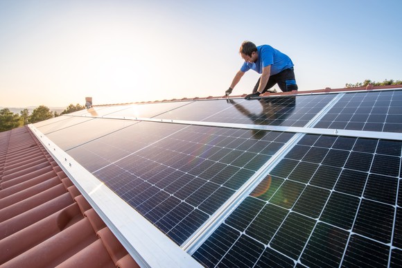 Worker installs solar panels on a roof. 
