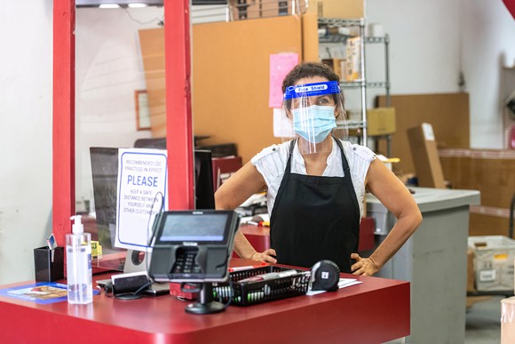 Person with clear plastic mask working at a shipping facility.