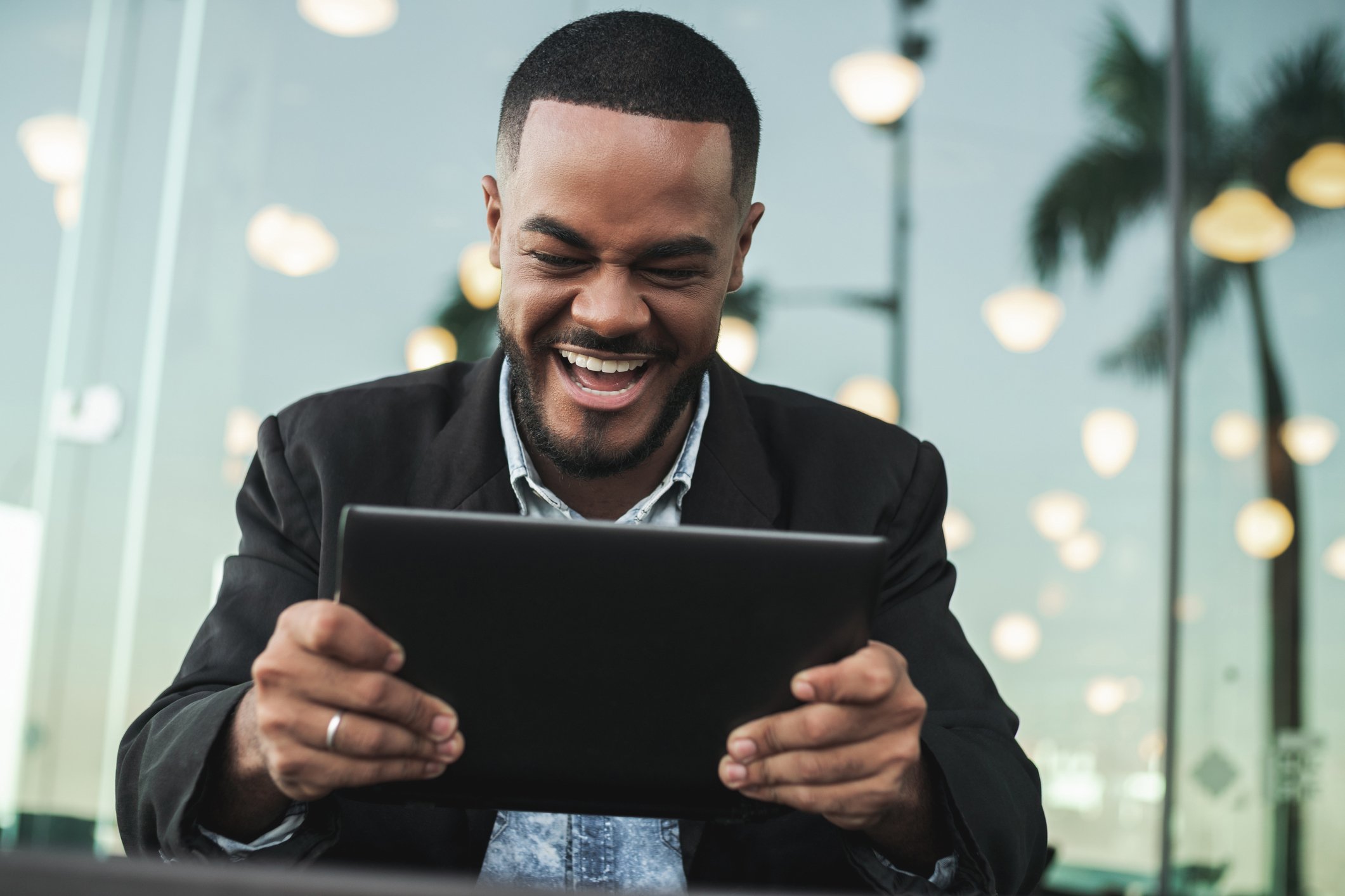 A person in business casual attire smiles at their tablet. 