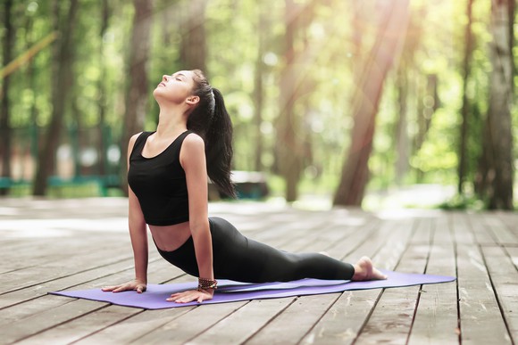 A person practicing yoga outdoors on a wooden deck. 