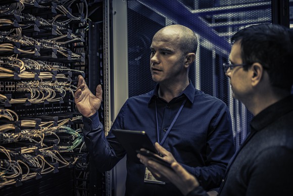 Two engineers talking in a server room.