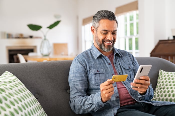 A person holding a credit card and making an online purchase.