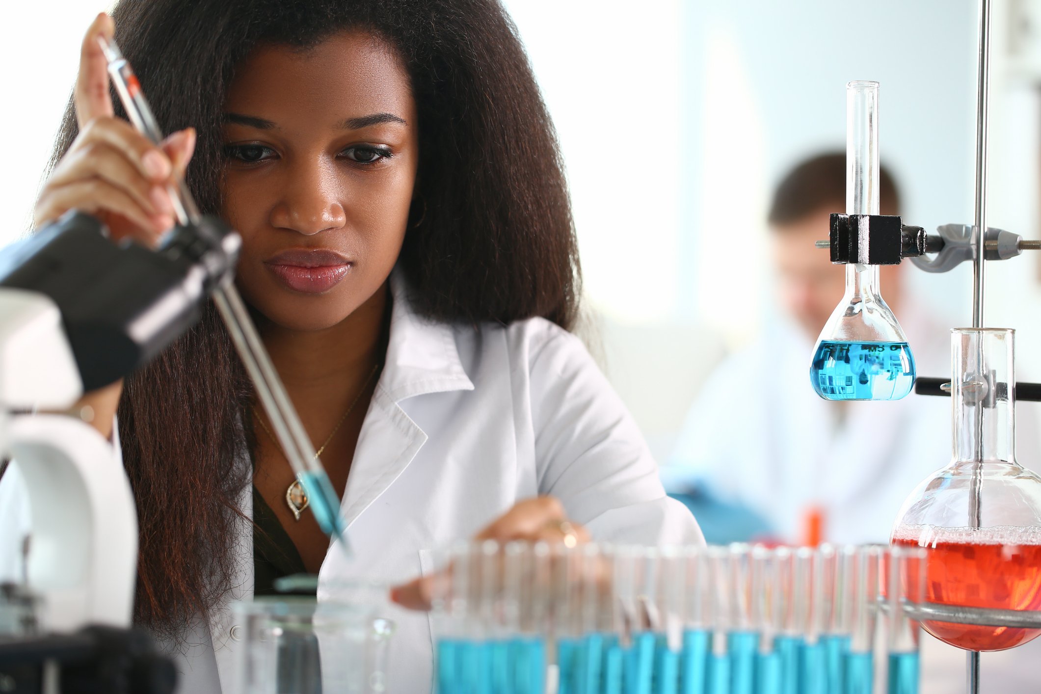 Scientists in white coats working with test tubes in a laboratory.
