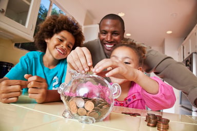 A family adding coins to a piggy bank.