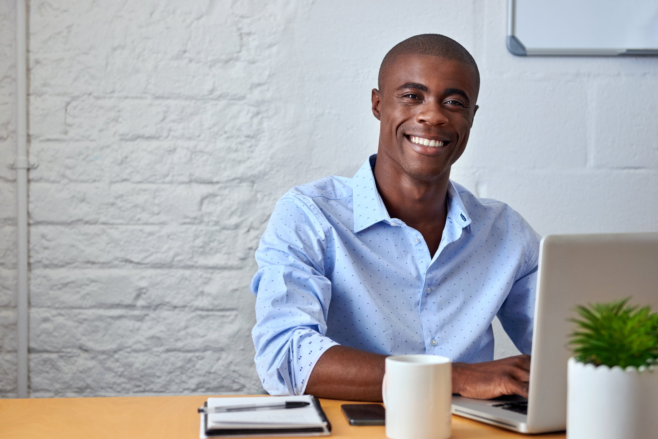 A smiling person at a laptop.
