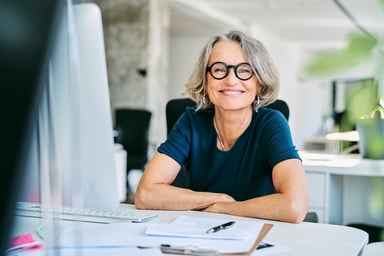 Smiling person at a desk_GettyImages-1261229865