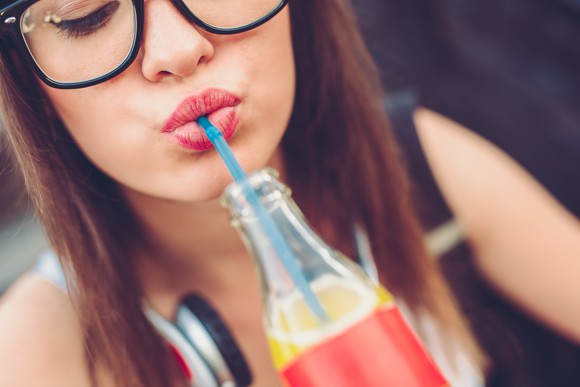 A person drinking a beverage with a straw.