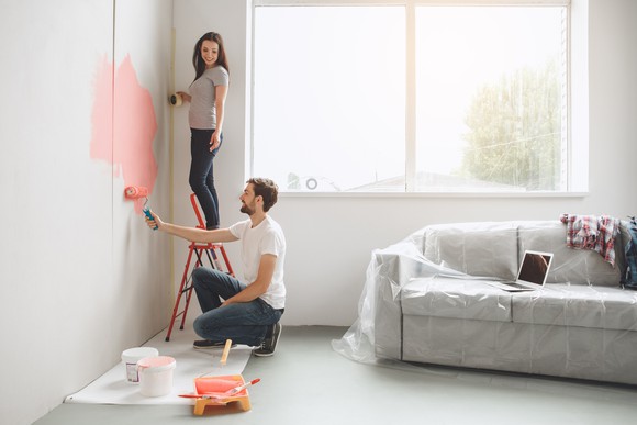Two people painting a wall.